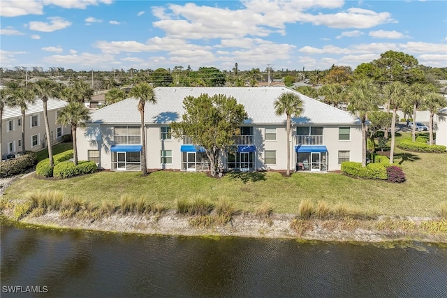 rear view of house featuring a yard and a water view