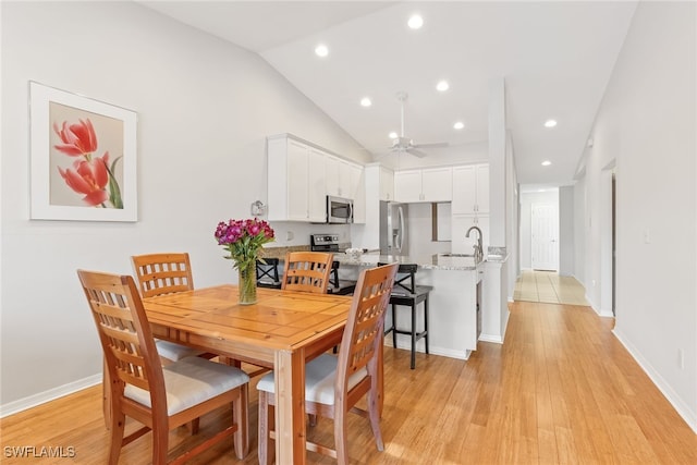 dining area with sink, vaulted ceiling, light hardwood / wood-style floors, and ceiling fan