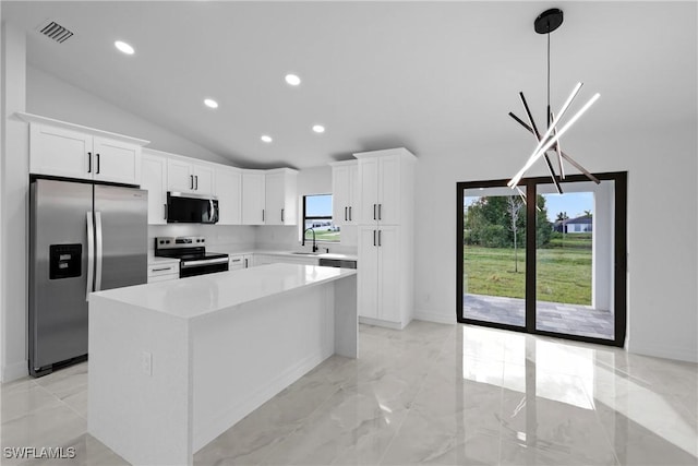 kitchen with white cabinets, decorative light fixtures, a kitchen island, and appliances with stainless steel finishes