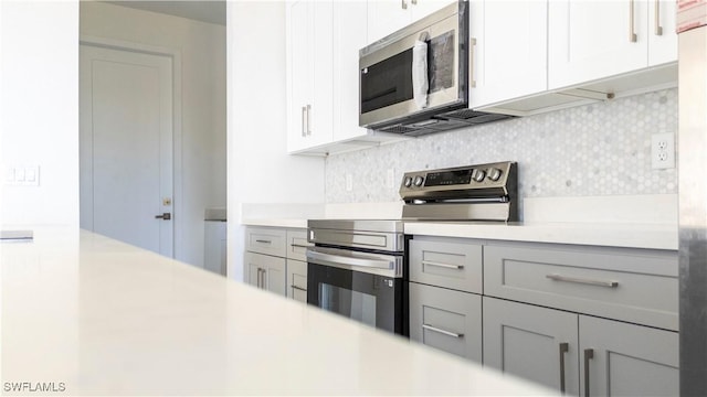 kitchen featuring white cabinets, backsplash, and appliances with stainless steel finishes