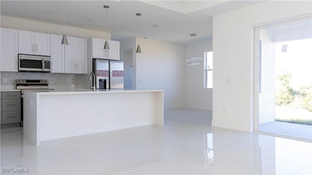 kitchen featuring decorative light fixtures, a center island with sink, appliances with stainless steel finishes, and backsplash