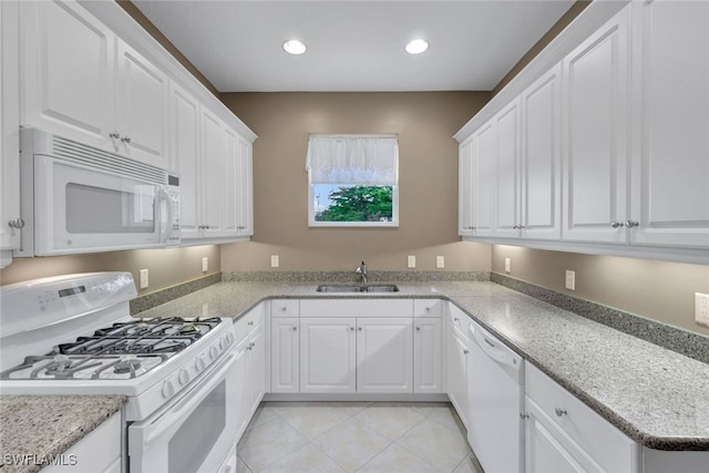 kitchen with white appliances, light stone counters, white cabinetry, light tile patterned flooring, and sink