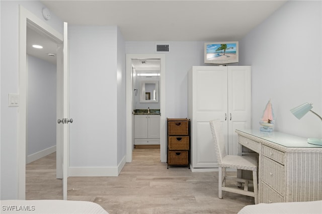 bedroom with light wood-type flooring, a closet, and sink