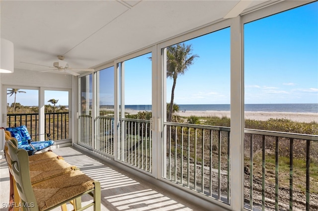 sunroom with a water view, plenty of natural light, and a beach view