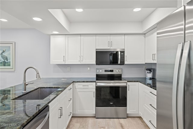 kitchen with dark stone countertops, sink, light hardwood / wood-style flooring, stainless steel appliances, and white cabinets