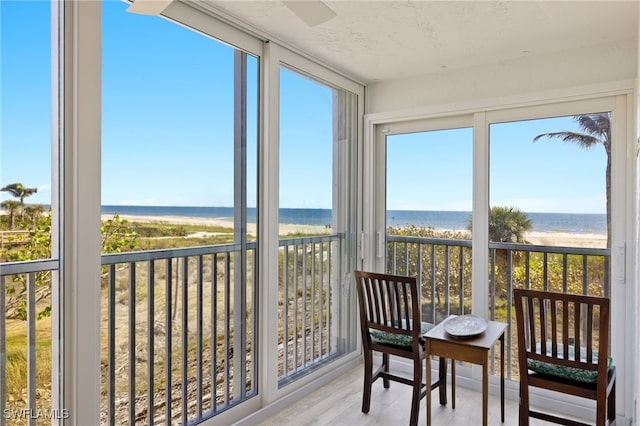 sunroom / solarium featuring a beach view and a water view