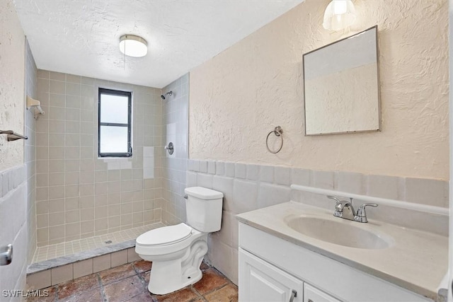 full bath with tile walls, toilet, a tile shower, a textured wall, and a textured ceiling