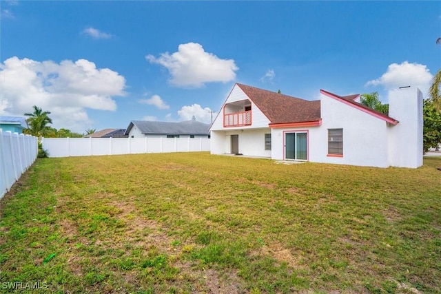 view of yard with a fenced backyard and a balcony