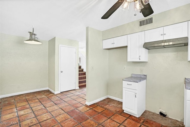 kitchen with under cabinet range hood, visible vents, white cabinetry, and baseboards