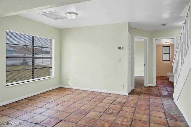 empty room with tile patterned flooring, stairs, baseboards, and visible vents