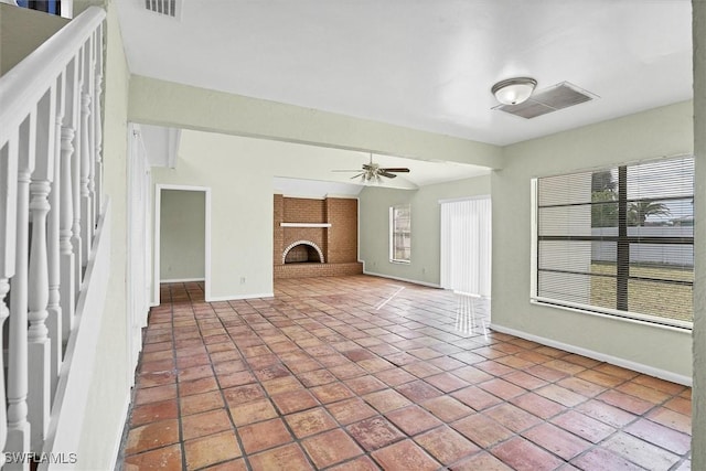 unfurnished living room with tile patterned flooring, visible vents, a fireplace, and a ceiling fan