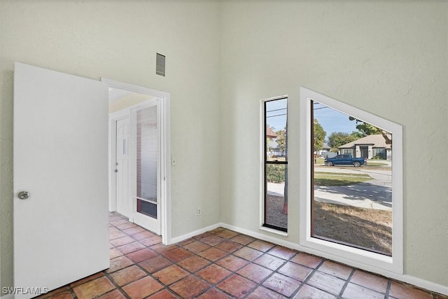 doorway to outside with visible vents, baseboards, and a towering ceiling