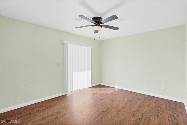 empty room featuring baseboards, wood finished floors, and a ceiling fan