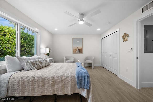 bedroom featuring light wood-type flooring, electric panel, ceiling fan, and a closet