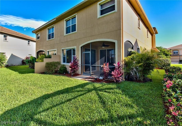 rear view of property featuring ceiling fan and a yard