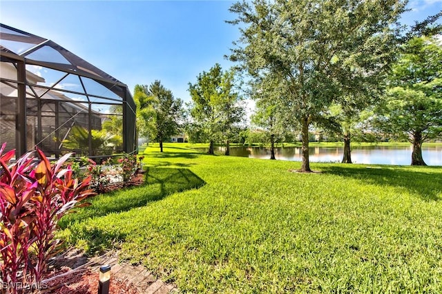 view of yard featuring glass enclosure and a water view