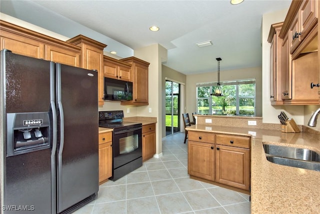 kitchen with light stone countertops, pendant lighting, light tile patterned floors, black appliances, and sink