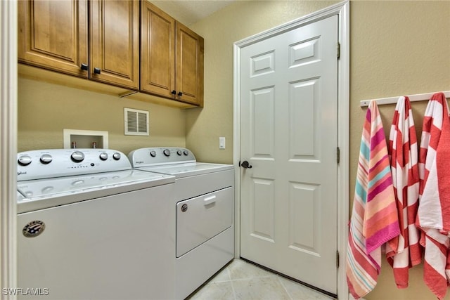 laundry room with light tile patterned floors, cabinets, and independent washer and dryer