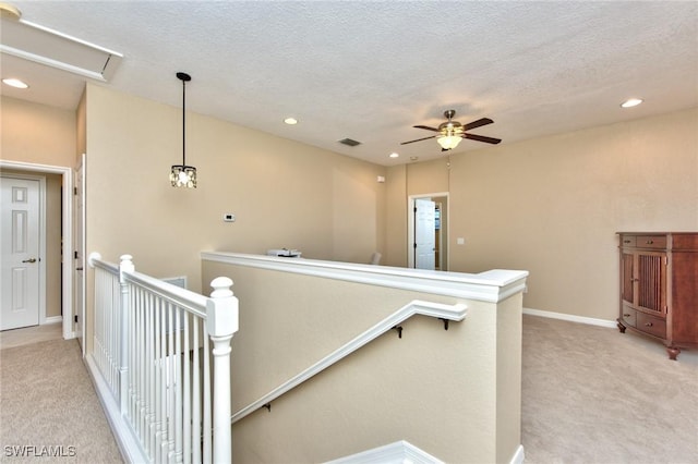 hall with a textured ceiling and light carpet