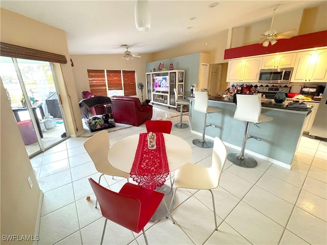 tiled dining space with ceiling fan and a towering ceiling