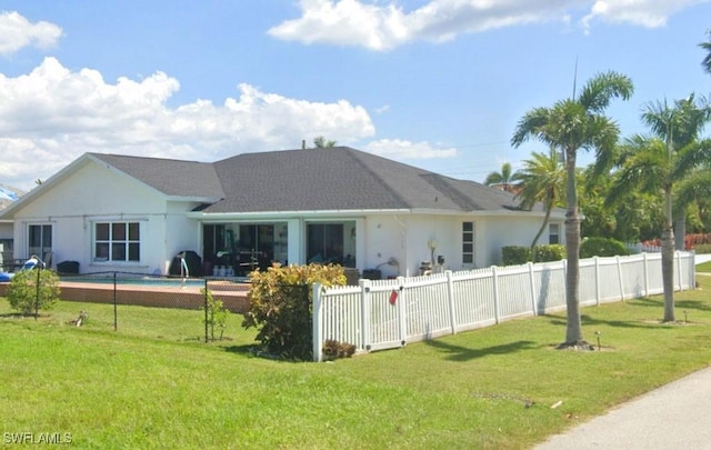 rear view of property with a lawn and a fenced in pool