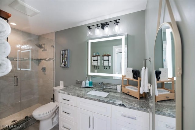 bathroom featuring vanity, an enclosed shower, and toilet