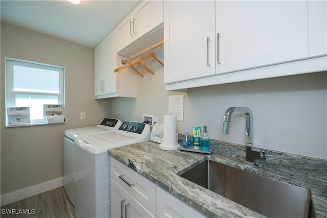 laundry room with cabinets, independent washer and dryer, wood-type flooring, and sink