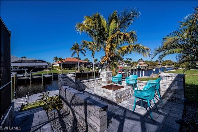 view of patio with a water view, a boat dock, and an outdoor fire pit