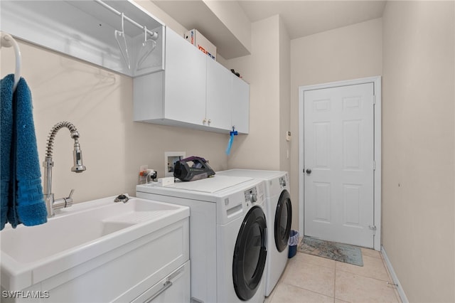 laundry area with light tile patterned flooring, cabinets, sink, and washing machine and clothes dryer