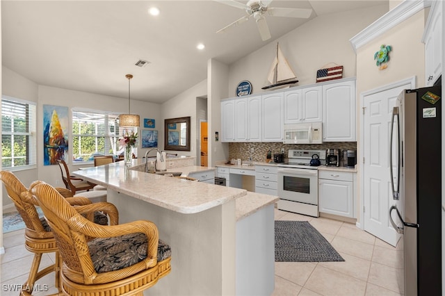 kitchen featuring a kitchen bar, white appliances, white cabinetry, hanging light fixtures, and lofted ceiling