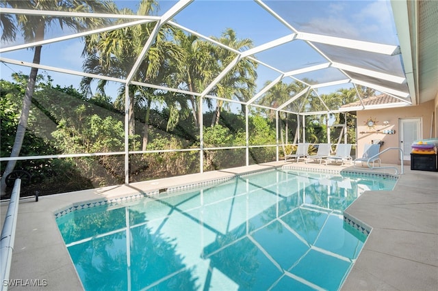 view of pool featuring glass enclosure and a patio area