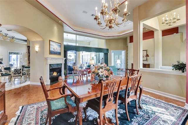 dining space with plenty of natural light, a raised ceiling, a fireplace, and hardwood / wood-style flooring