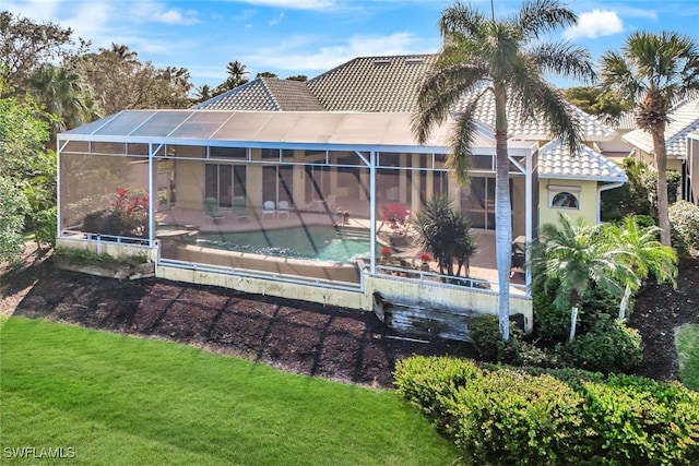 rear view of property with a lanai and a lawn