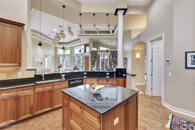 kitchen with kitchen peninsula, light hardwood / wood-style floors, dark stone counters, black dishwasher, and sink