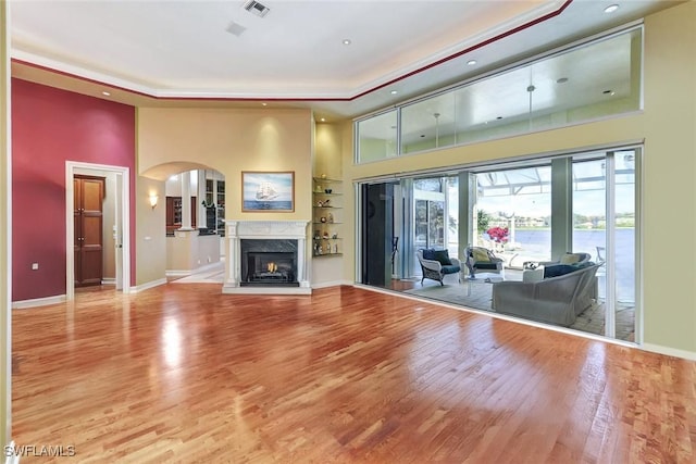 4200 Sanctuary Way, Bonita Springs, FL 34134 - unfurnished living room featuring a high ceiling, wood finished floors, a tray ceiling, arched walkways, and recessed lighting