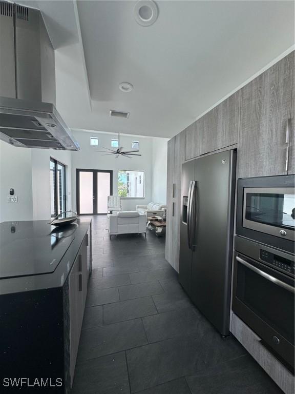 kitchen featuring ceiling fan, wall chimney range hood, and stainless steel appliances