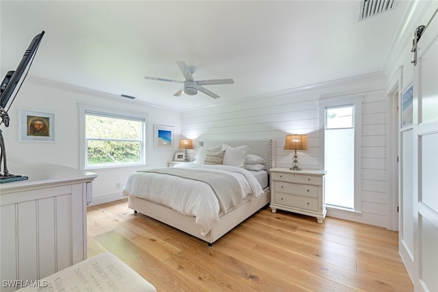 bedroom with crown molding, ceiling fan, light hardwood / wood-style floors, and multiple windows