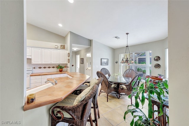 tiled dining room featuring vaulted ceiling