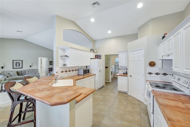 kitchen with wood counters, a kitchen bar, kitchen peninsula, white appliances, and white cabinets