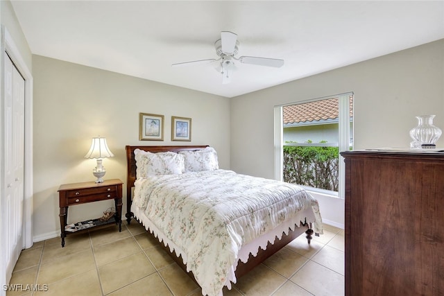 bedroom with a closet, light tile patterned flooring, and ceiling fan