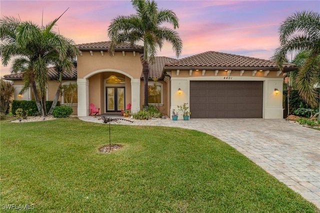 mediterranean / spanish-style home with a garage, a yard, and french doors