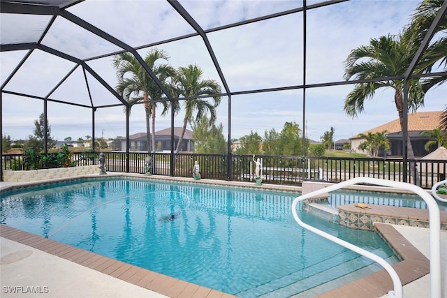 view of pool with a patio, glass enclosure, and an in ground hot tub