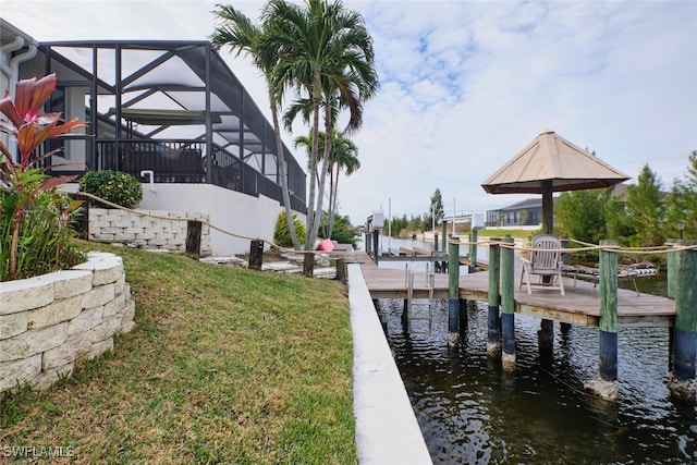 view of dock with glass enclosure, a water view, and a yard