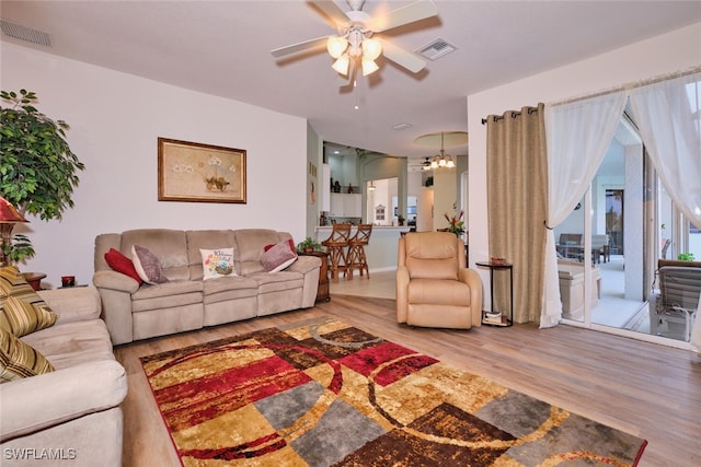 living room featuring ceiling fan with notable chandelier and hardwood / wood-style flooring