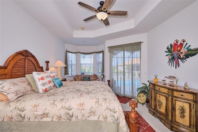 bedroom with ceiling fan, a raised ceiling, and access to outside