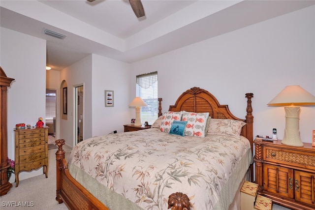 bedroom with ceiling fan, light colored carpet, and connected bathroom