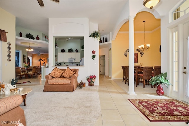 tiled living room featuring crown molding, an inviting chandelier, and decorative columns