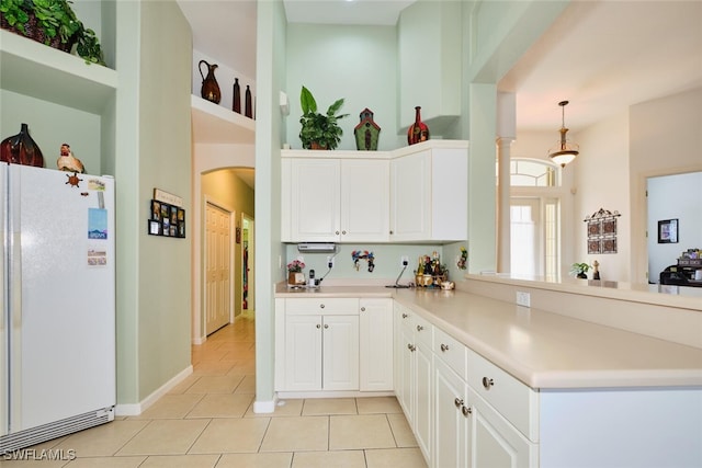 kitchen with decorative light fixtures, white cabinetry, white fridge, kitchen peninsula, and light tile patterned floors