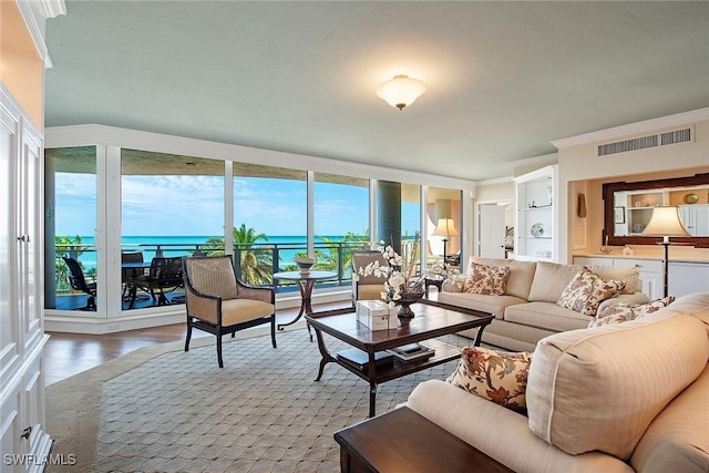 living room featuring hardwood / wood-style flooring, crown molding, and a water view