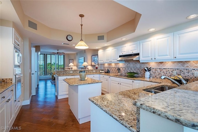 kitchen featuring kitchen peninsula, hanging light fixtures, a kitchen island, white cabinets, and sink